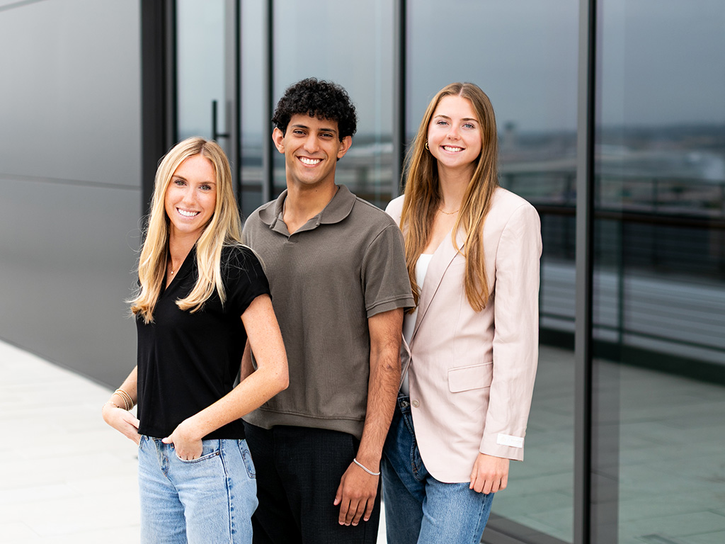 Colrich Interns - 3 interns standing in front of a large glass window